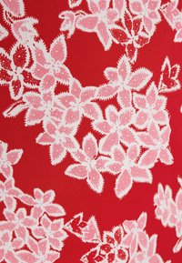 Tissu rouge avec un motif floral comprenant des feuilles et des fleurs roses, détaillé avec des contours et des textures qui améliorent le design.