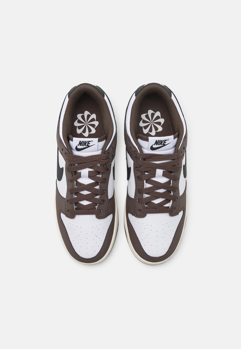 Les sneakers Nike présentent un schéma de couleurs marron et blanc, des matériaux en cuir et en mesh, des détails perforés, un col rembourré et des accents de logo.