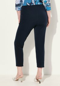 Mörkblå slim fit-byxor med en jämn yta, med en midja i normalhöjd och avsmalnande ben. Tillsammans med silverfärgade öppna klackar.