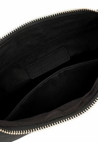 Clutch en tissu noir avec une fermeture éclair argentée, présentant un intérieur lisse, deux compartiments, et une étiquette en cuir marquée "EMILY & NOAH."