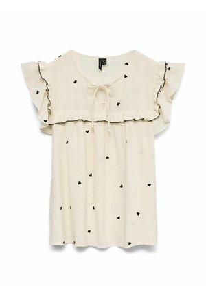 Top en crème clair avec des manches courtes à volants, présentant des motifs de cœurs noirs et une fermeture à nouer au niveau du col, avec un ourlet à volants.