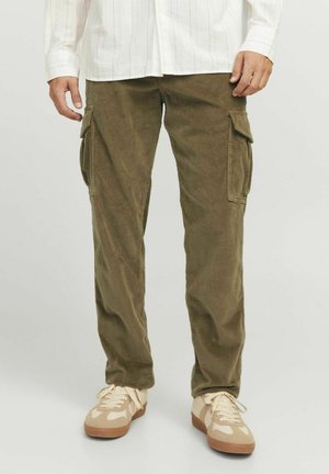Un pantalon cargo en velours côtelé vert olive avec poches latérales, jambes droites et une texture douce, associé à des baskets beiges et une chemise blanche à boutons.