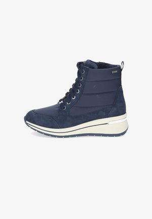 Navy blue mid-top sneaker made of smooth and suede materials, featuring a white sole, metal eyelets, and a pull tab at the heel.