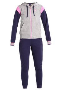 Sweat à capuche gris zippé avec manches rose clair et marine, associé à un pantalon de jogging marine avec des détails rose clair.