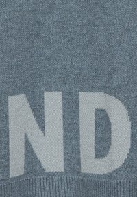 Tessuto a maglia blu con grandi lettere bianche che formano "ND," con una texture liscia e un sottile motivo mélange.