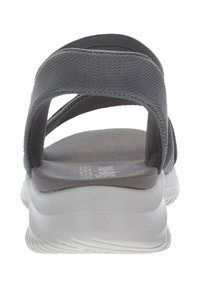 Sandalia gris con diseño de tiras cruzadas, parte superior de tejido texturizado, suela acolchada y suela exterior de goma blanca gruesa. Aspecto minimalista elegante.