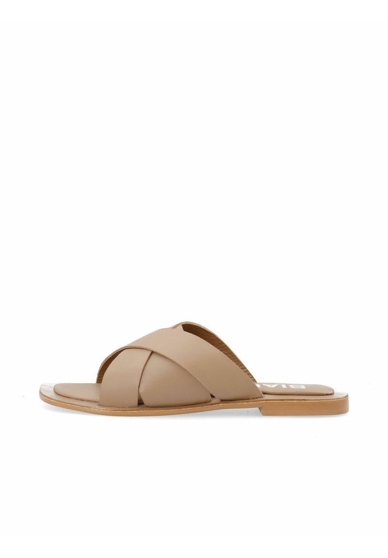 Infradito in pelle beige con design a fascette incrociate, suola piatta e accenti marrone chiaro. Texture liscia con uno stile semplice e minimalista.