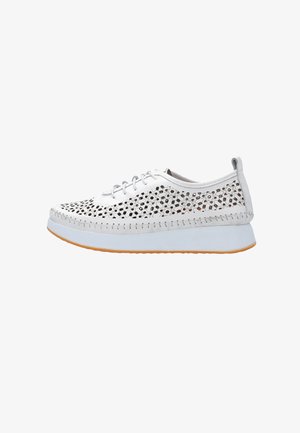 White lace-up sneaker with perforated floral cutouts, thick white sole, and beige rubber outsole, shown from the side on a white background.