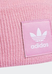 Ružová pletená čiapka s textúrovaným vzorom a štvorcovou nášivkou so znakem bieleho Adidas a dizajnom s tromi pruhmi.