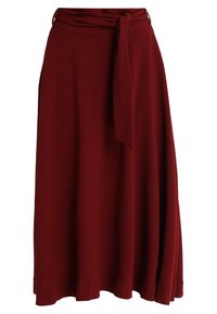 Longue jupe bordeaux en tissu doux et léger. Elle présente une taille nouée et une silhouette fluide avec une texture lisse.