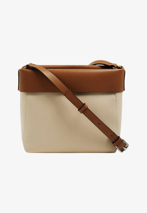Bolso estructurado con un cuerpo de color crema y solapa de cuero marrón. Presenta una correa ajustable y detalles en acero inoxidable. Textura suave.