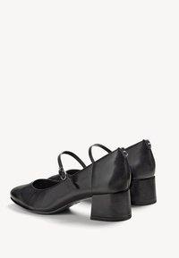 Black leather heeled shoes feature a rounded toe, ankle straps with buckles, and a block heel, providing a smooth texture and classic design.