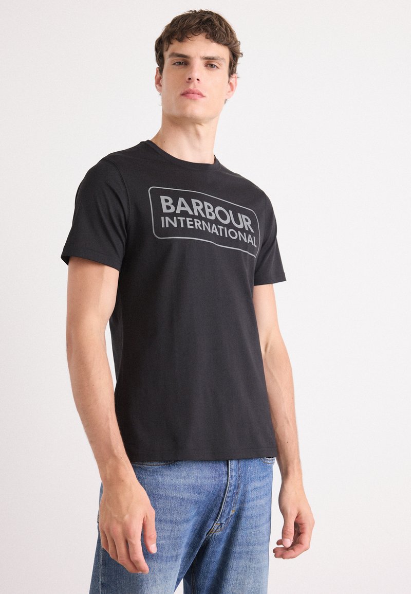 Tricou din bumbac negru, cu un mare logo gri "BARBOUR INTERNATIONAL" pe față. Croiala clasică, cu mâneci scurte �și guler rotund.