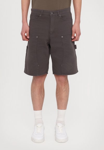 Graue Cargo-Shorts aus Baumwolle mit mehreren Taschen, lockerer Passform und geradem Schnitt, kombiniert mit weißen Sneakers und Socken.