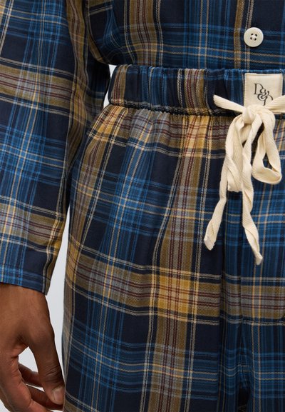 Rutigt lounge-set i blå, bruna och gula toner. Har en knappstängd topp och dragsko i midjan på byxorna med texturerat tyg och resårmidja.