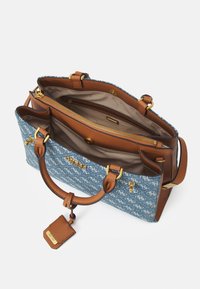 Torba z materiału w niebieskie wzory z brązowymi skórzanymi akcentami, wyposażona w zamykaną na zamek wewnętrzną przegrodę i górne uchwyty. Widoczne złote elementy metalowe.