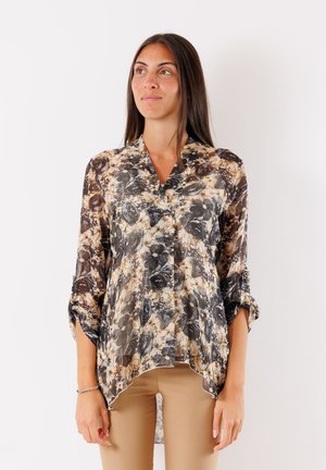 Blusa floreale trasparente con una combinazione di colori crema, nera e dorata. Presenta una scollatura a V, maniche a tre quarti e un orlo alto-basso.