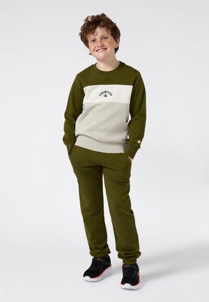 Sudadera verde oliva con franjas crema, logo de "Champion". Joggers a juego en verde oliva y zapatillas negras con acentos rojos. Ajuste cómodo.