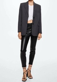 Dark grey tailored blazer with notch lapels, single-button front, worn over a cropped white shirt and paired with black leather pants and strappy heels.