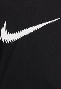 Czarna tkanina o gładkiej fakturze z dużym białym logo Nike w kształcie dynamicznego, ostrego łuku.
