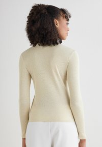 Jasnożółty sweter z prążkowanej dzianiny z długimi rękawami i dopasowanym krojem, z subtelną fakturą i czystą, minimalistyczną sylwetką.