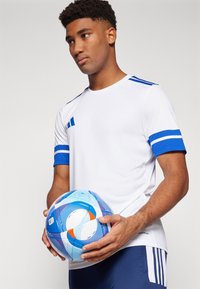 White athletic shirt with blue stripes, paired with navy shorts. The person holds a multicolored blue and orange soccer ball with swirl patterns.