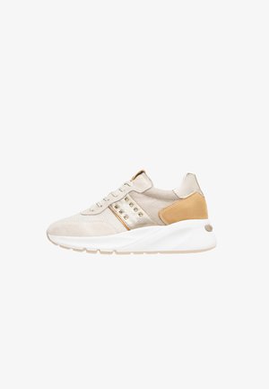 Beige sneaker gemaakt van suede en mesh, met gouden accenten, een gestructureerd oppervlak en een chunky witte zool. Inclusief studs aan de zijkant.