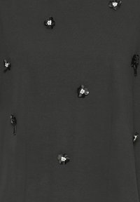 Black T-shirt with a smooth texture, featuring black floral appliqués and small rhinestone accents arranged throughout the fabric.