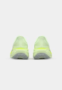 Vista trasera de zapatillas de correr verde claro con parte superior de malla transpirable y talón acolchado. Presenta una suela texturizada para mayor tracción.