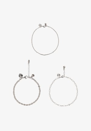Drie zilveren armbanden: één met een fijne schakelketting, één met een gestructureerde accenthanger, en één met een combinatie van gladde en schakeldesigns.