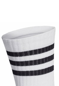 Weißer Socken mit drei horizontalen schwarzen Streifen. Gerippte Textur oben. Der Stoff ist glatt und dehnbar, designed um eng zu sitzen.