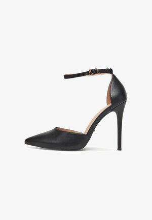Černé stiletto podpatky s špičatou špičkou, kotníkovým páskem a zlatou sponou, uzavřenou zadní částí a hladkým koženým povrchem.