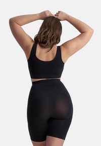 Sujetador deportivo negro y shorts de talle alto con textura suave, presentando un diseño ajustado y una banda ancha en la cintura. Vista posterior.