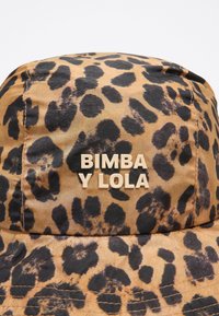 Bežinė ir juoda leopardų rašto kibiro skrybėlė, pagaminta iš tekstūruotos medžiagos, priekyje su iškilniu "BIMBA Y LOLA" logotipu.