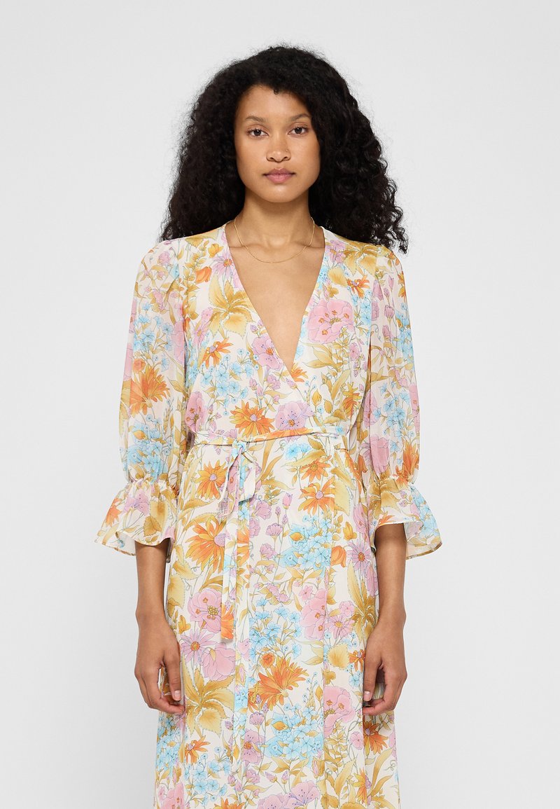 Floral wrap dress in pastel colors with a v-neck, flared sleeves, and a cinched waist. Features a light, flowing fabric with colorful flower patterns.