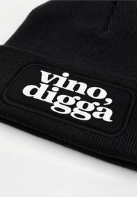 Black beanie with ribbed texture, featuring a rectangular black patch and white text reading "vino, diggà." Simple, functional design.