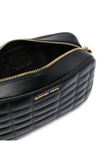 Borsa in pelle nera trapuntata con zipper dorato e etichetta con logo all'interno. Texture liscia e forma tondeggiante, apertura dall'alto.