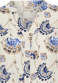 Kvetovaná blúzka na zapínanie na gombíky s bielym pozadím a modrými, námorníckymi a hnedými kvetinovými vzormi. Textúrovaná látka s jemným leskom.
