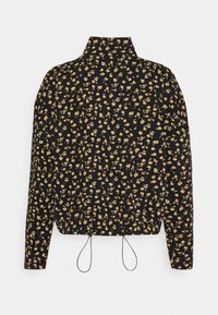 Blouse noire à manches longues avec col montant, petit motif floral jaune et cordons ajustables à l'ourlet.