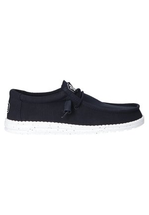 Navy canvas boat shoes with a white speckled rubber sole, rounded toe, lace-up detail, and a logo tag on the side.