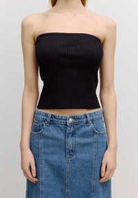 Zwart geribbeld strapless top met een cropped ontwerp, gecombineerd met een hoog-was blauwe denimrok met knopen en zakken.