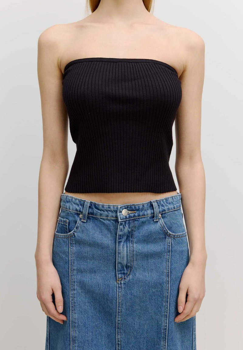 Zwart geribbeld strapless top met een cropped ontwerp, gecombineerd met een hoog-was blauwe denimrok met knopen en zakken.