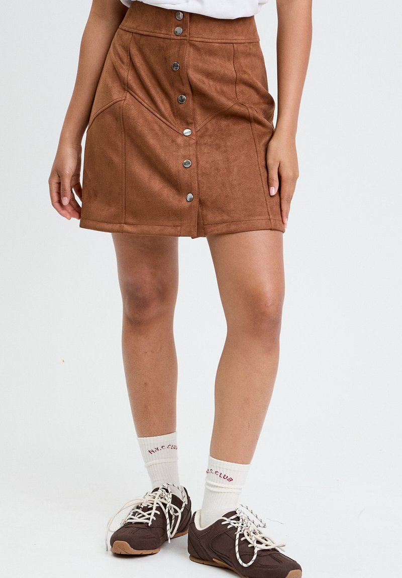 Brown suede mini nederdel med høj talje, frontknaplukning og sidelommer, med en glat tekstur og tætsiddende form.