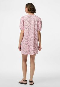 Růžové květinové šaty s nafouknutými rukávy, volného střihu a délkou po kolena. Uzdobené malými květinovými vzory.