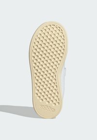 Bijeli tenisice s teksturiranom gumenom potplatom koja ima uzorak u obliku saća. Ime brenda "adidas" urezano je sa strane potplata.