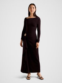 Long-sleeve, form-fitting dress in deep purple fabric, featuring a draped side ruffle and a decorative gold flower accent.