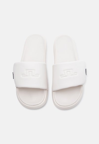 Ζευγάρι λευκών σανδαλιών σλάιντ με επενδυμένες λουρίδες που φέρουν ένα διακριτικό ανάγλυφο λογότυπο σε κάθε λουρί, πάνω σε απλό φόντο.