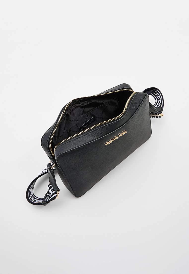 Czarna skórzana torba z złotymi akcentami, zamknięcie na zamek i wzorzystym paskiem. Wnętrze ma pikowaną teksturę. Nazwa marki wytłoczona z przodu.