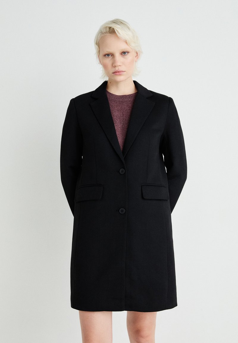 Čierny štruktúrovaný kabát s dvoma prednými vreckami, zapínaním na jeden gombík a klopovými límci. Mäkká tkanina s hladkou textúrou.