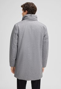 Grau melierter Wollmischmantel mit hohem Kragen, subtilen Mustern und einem Knopfdetail auf der Rückseite. Hat einen lockeren Schnitt und ein mittellanges Design.